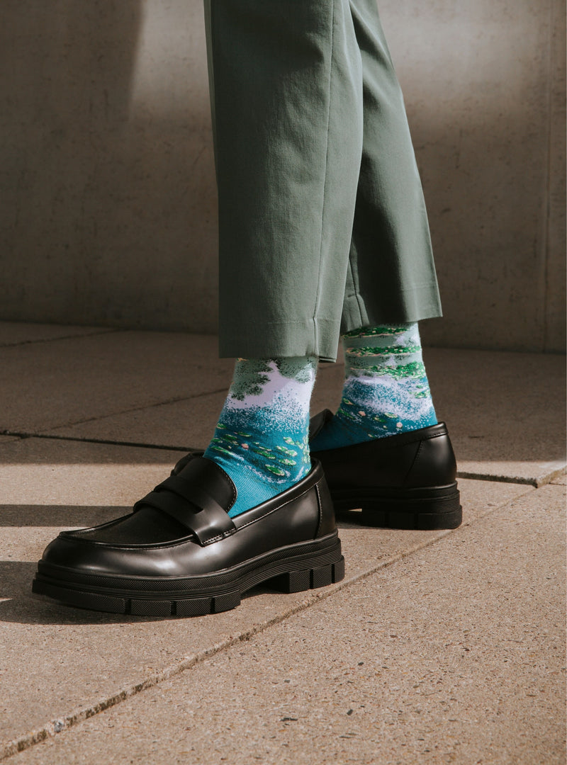Waterlelies sokken van Kunstsokken naar Claude Monet, gedragen met zwarte loafers en een groene broek